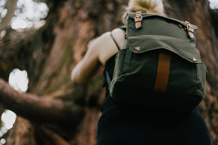Dívka s batohem na zádech jde přes les
