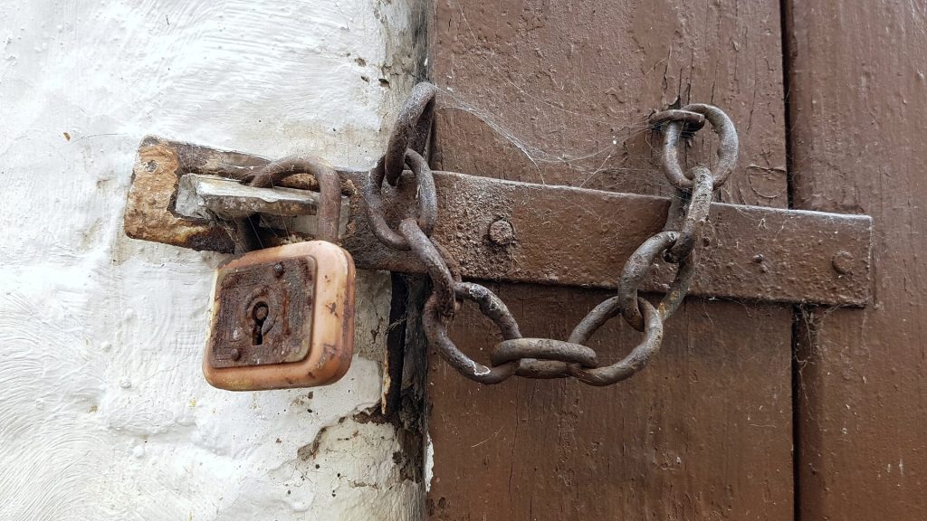 Rezavý řetěz a visací zámek na starých dveřích 