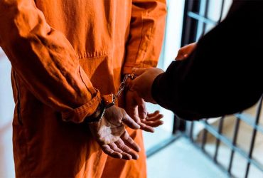 vězeň v oranžové uniformě se spoutanými rukami