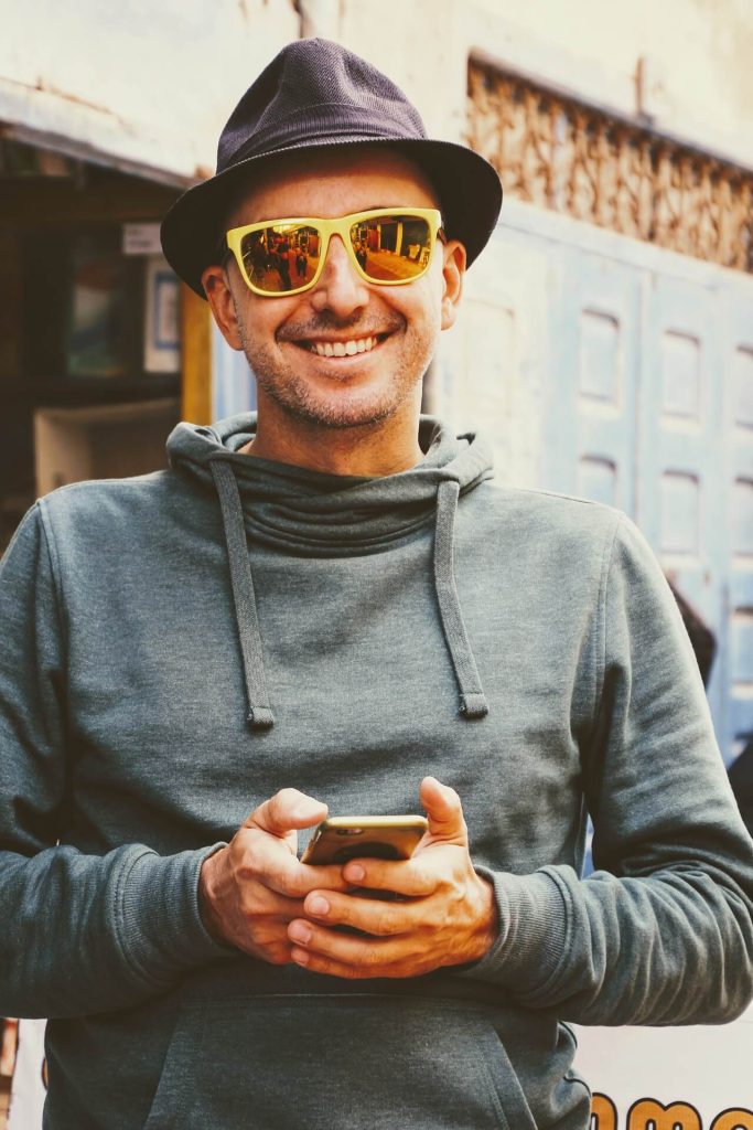 mladý muž ve slunečních brýlích s mobilem v rukou