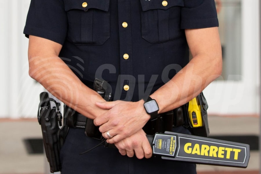 Pracovník ostrahy drží ruční detektor kovů
